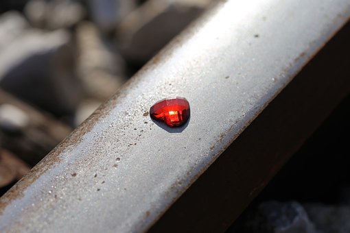 a tiny red gemstone placed on a metal railroad track